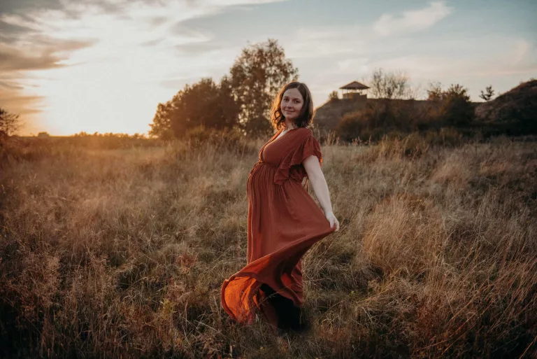 Schwangere steht mit schönem Kleid im Feld