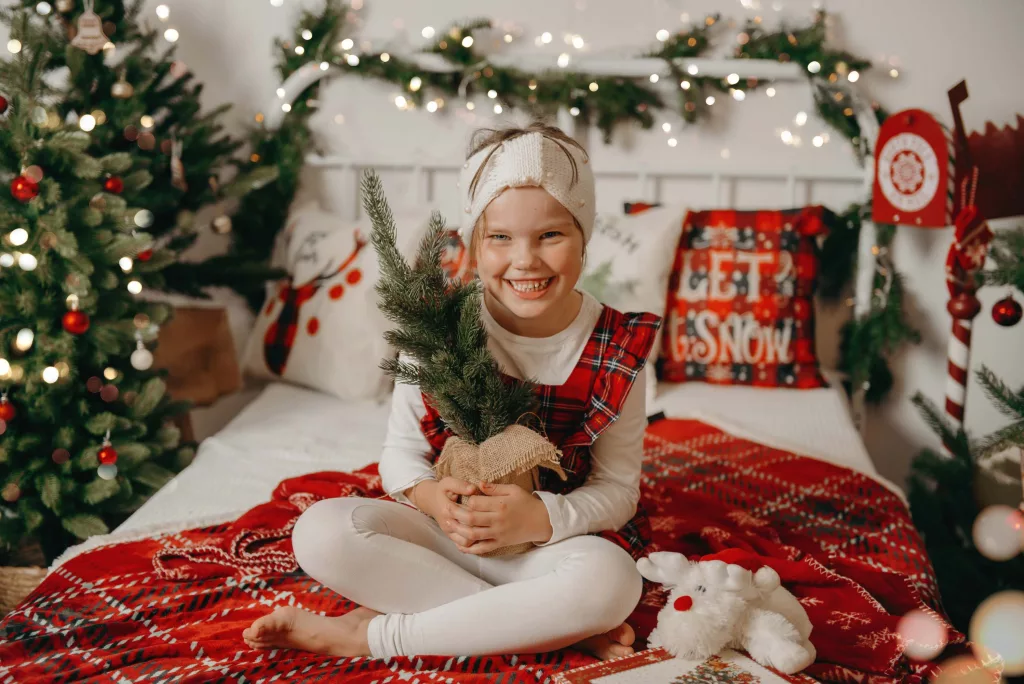 Mädchen sitzt auf einem Weihnachtsbett